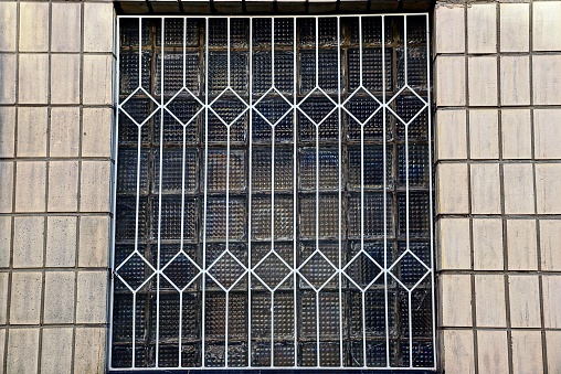 iron grating on a glass window on the brown wall of the house