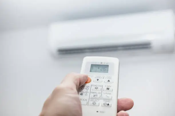 Photo of air conditioner closeup hand with remote control