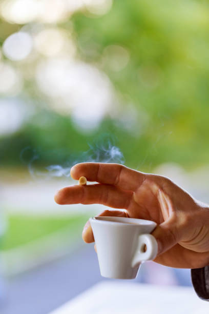 istock close up man's hand with cup of black coffee and a cigarette 867056560