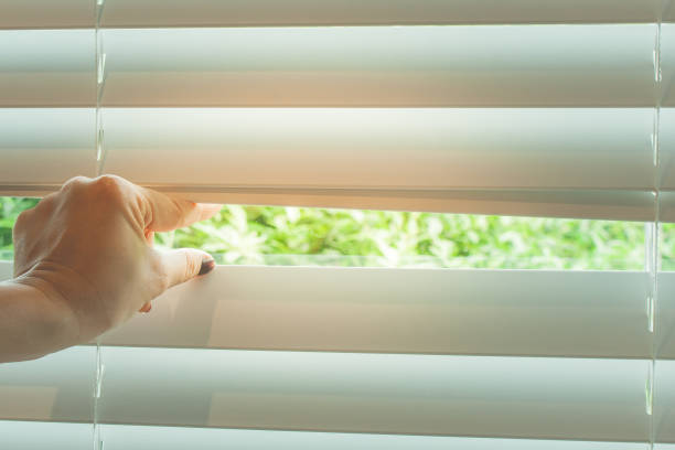 istock Close up woman hand taking a peak through the window blinds. 867071984