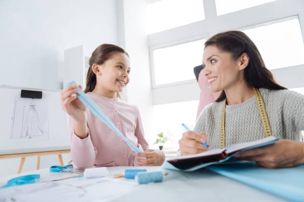 attractive creative woman smiling to her daughter - mannequin dressmakers model tape measure female imagens e fotografias de stock