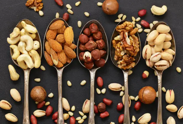 various kinds of nuts (cedar, cashew, hazelnuts, walnuts) in spoons