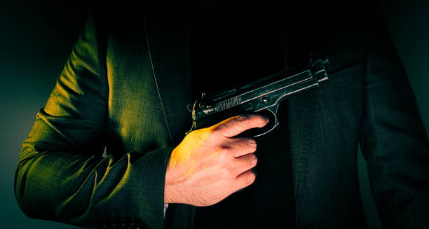 istock Hitman in suit  holds gun in front of himself 867090680
