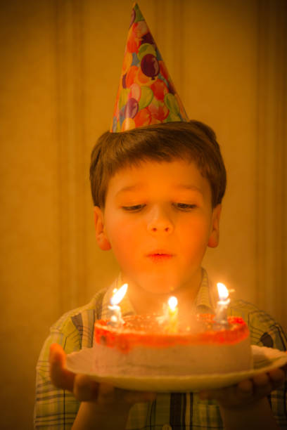 istock Boy blowing to burning candles at birthday cake 867090772
