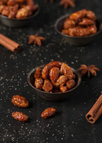 Homemade candied almonds with brown sugar and cinnamon on dark rustic background.