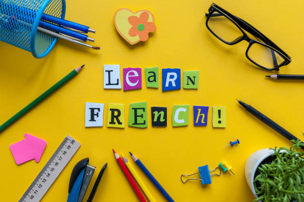 word 學習法語與辦公室或學校用品, 文具在黃色的辦公桌上雕刻的字母。法語語言課程的概念 - 法語 個照片及圖片檔