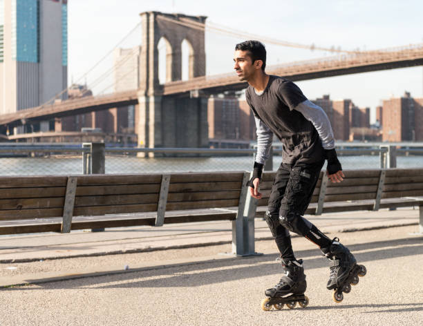 Inline Skating in New York Side view of a man as he inline skates in Brooklyn, with the Brooklyn Bridge and the buildings of Manhattan Island in the background. inline skating stock pictures, royalty-free photos & images