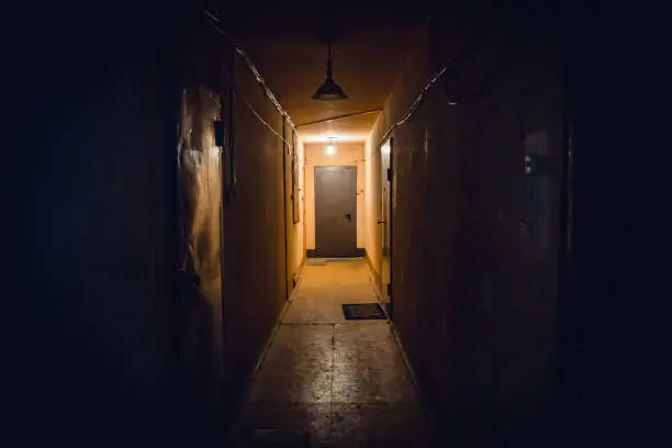 Photo of Dirty empty dark corridor in apartment building, doors, lighting lamps