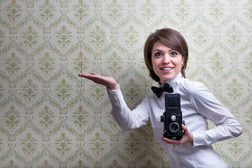 vintage photographer showing some copyspace in her hand in front of a vintage background
