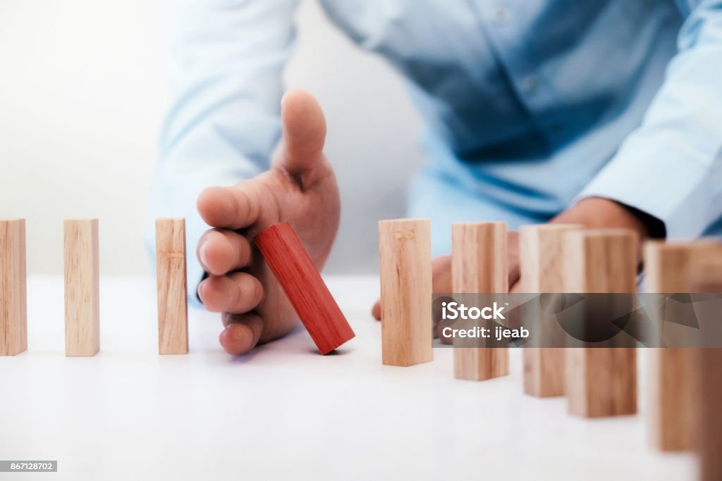 Business risk, strategy and planing concept idea. Businessman hand stop dominoes continuous toppled or risk with copyspace. Business risk, strategy and planing concept idea. Risk Stock Photo
