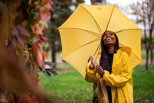 Woman Awaiting For Rain Under Yellow Umbrella On Long Walk At Park On Autumn Day