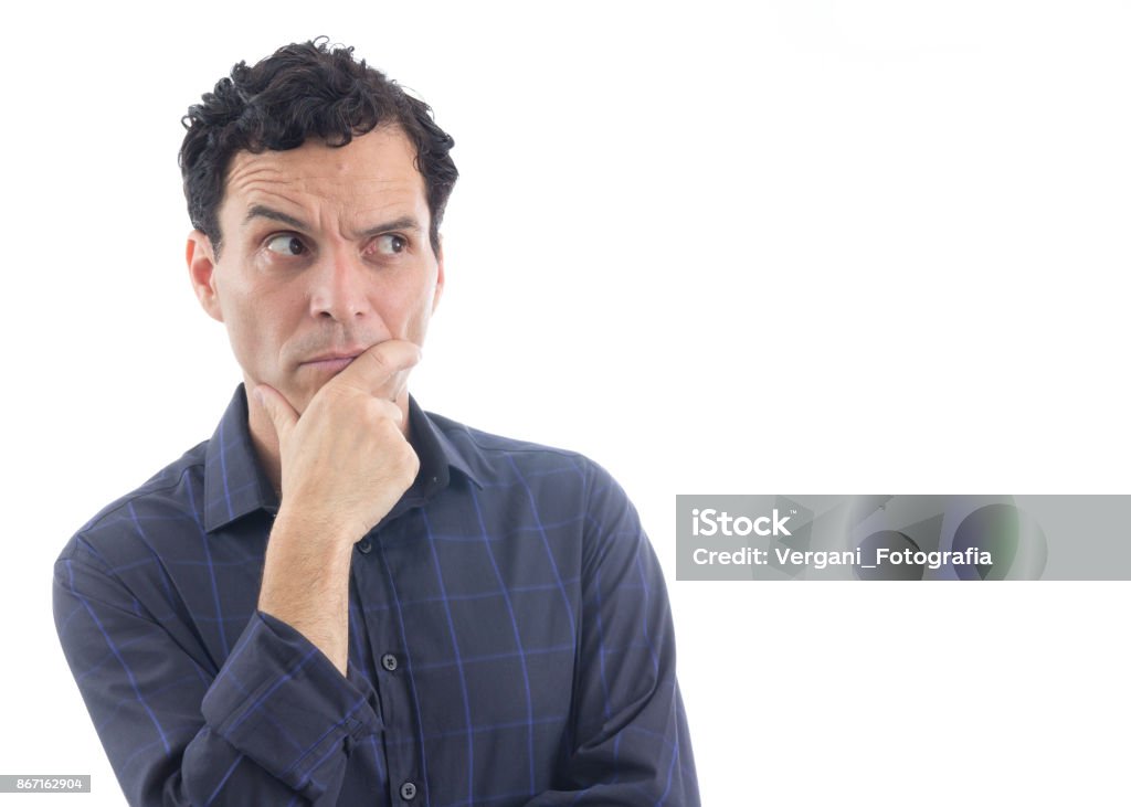 Suspicious man. The person is wearing dark blue social shirt. Isolated."n A suspicious man has his hands resting on his chin. He looks to the side. The person is Caucasian and is wearing blue button-down shirt. Isolated. White background. Suspicion Stock Photo