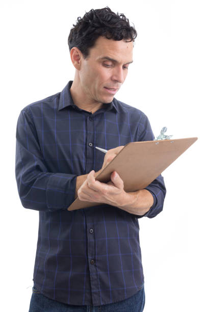 Worker takes notes and holds a clipboard. The person is wearing dark blue social shirt. Isolated."n Worker man is making notes. He is writing on a drawing board. The person is Caucasian and is wearing blue button-down shirt. Isolated. White background. man writing on white board stock pictures, royalty-free photos & images