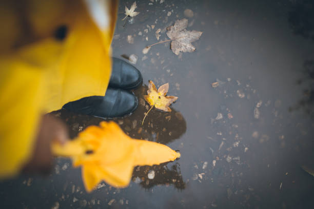 Photo of yellow rubber boots on rocks and asphalt, these shoes are usually worn by workers and farmers, these boots are waterproof