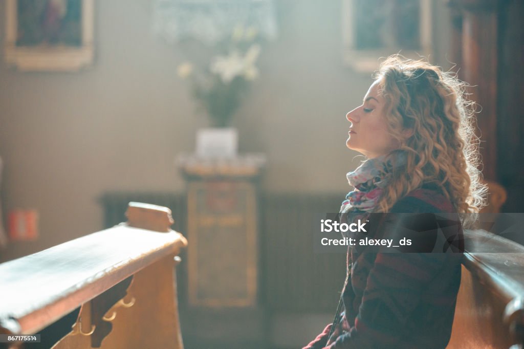 Jeune femme priant dans l’église. - Photo de Église libre de droits