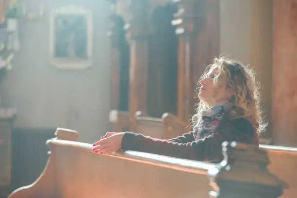 Photo of Young woman hopefuly praying in the church.