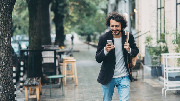 homem enviando mensagem de celular com na cidade - tourist backpack smiling cheerful - fotografias e filmes do acervo