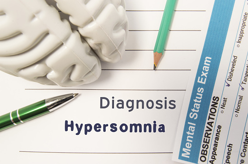 Diagnosis Hypersomnia. Figure of human brain, result of mental status exam, pen and pencil surrounded written psychiatric diagnosis Hypersomnia in medical report on doctor deck. Concept for psychiatry