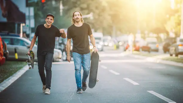 Photo of Two pro skateboard rider ride skate through cars on street