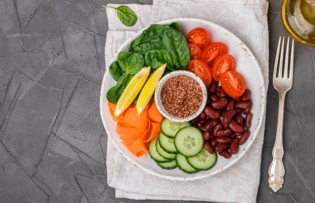 istock Vegetarian buddha bowl. Raw vegetables - tomatoes, cucumbers, beans, spinach, carrots, lemon and flax seed in a bowl. healthy, detox food concept. Selective focus. Top view, Copy space 867199812