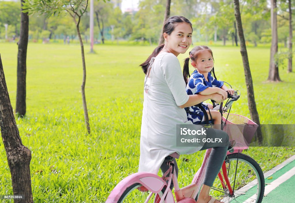 Asian mother and her child girl on a bike at the park in the morning. Active Lifestyle Stock Photo