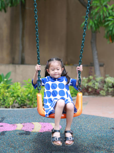 istock Asian little enjoy playing swing in the playground. 867203890