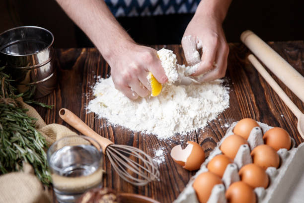 istock A man breaks an egg yolk into white flour on a kitchen table. 867204204