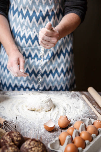 istock A cook with one hand pours flour on a round dough. 867207284