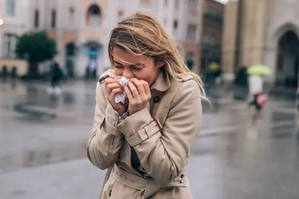 A beautiful young woman blowing her nose in public.