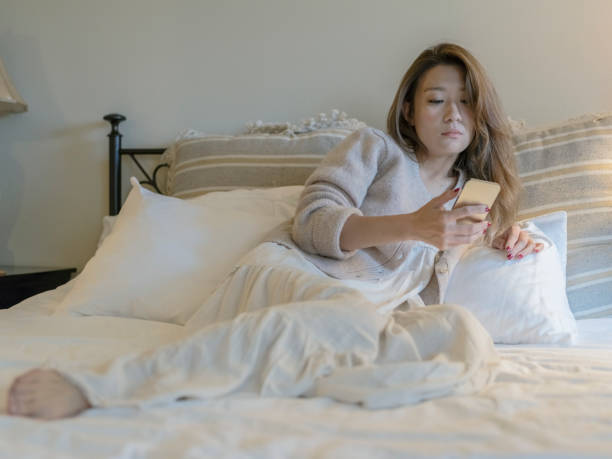 woman lying on bed looking at cellphone