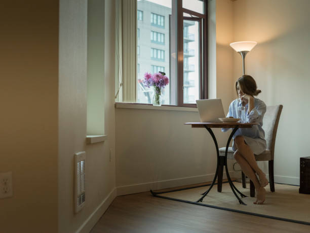istock woman in shirt using laptop with breakfast on table 867226164