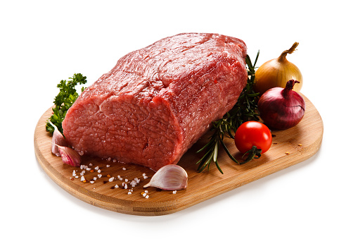 Raw sirloin beef on cutting board and vegetables on white background