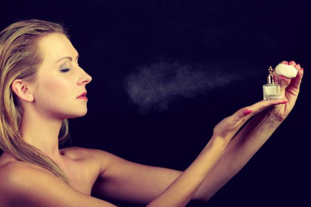 istock Beautiful woman with holding and applying perfume 867269482