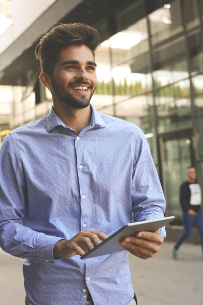 istock Smiley businessman walking on street and using iPod. 867273358