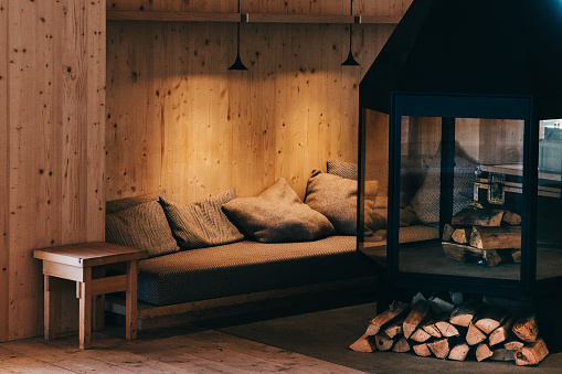 Cosy fireplace with pillows and tree logs ready to get relaxed at