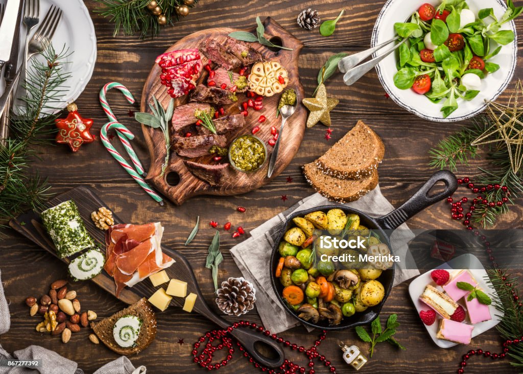 Christmas themed dinner table Flat lay of Delicious Christmas themed dinner table with roasted meat steak, appetizers and desserts. Top view. Holiday concept. Christmas Stock Photo