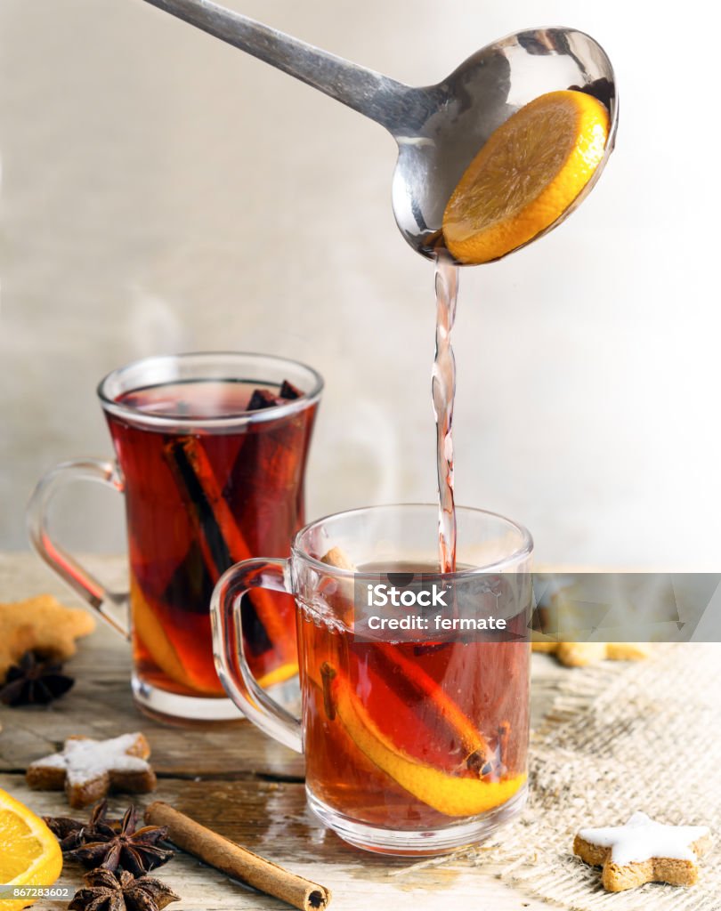 pouring mulled wine in glass mugs, Christmas cookies and spices like orange, cloves, star anise and cinnamon, rustic wooden table, bright background, vertical pouring mulled wine in glass mugs, Christmas  cookies and spices like orange slices, cloves, star anise and cinnamon, rustic wooden table, bright background, vertical, selected focus Mulled Wine Stock Photo