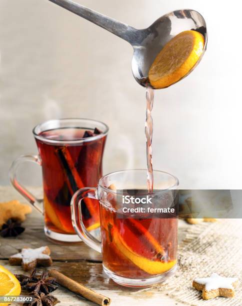 Pouring Mulled Wine In Glass Mugs Christmas Cookies And Spices Like Orange Cloves Star Anise And Cinnamon Rustic Wooden Table Bright Background Vertical Stock Photo - Download Image Now