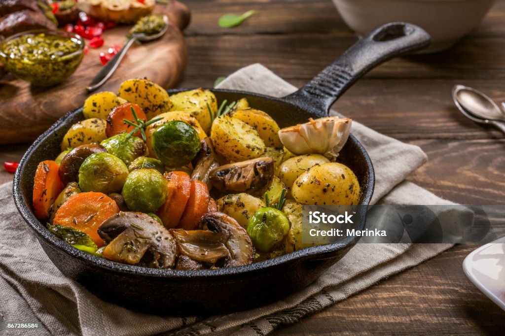 Fried potatoes with vegetables Fried potatoes with vegetables and herbs on wooden background. Healthy food concept. Roasted Stock Photo