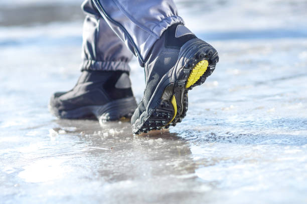 gambe invernali che indossano stivali che camminano su strada innevata e nevischio - road ice danger winter foto e immagini stock