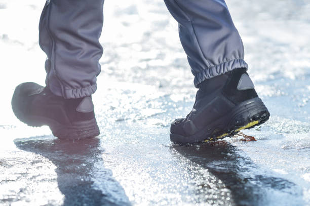 istock Winter legs wearing boots walking on snowy and sleet road 867287282