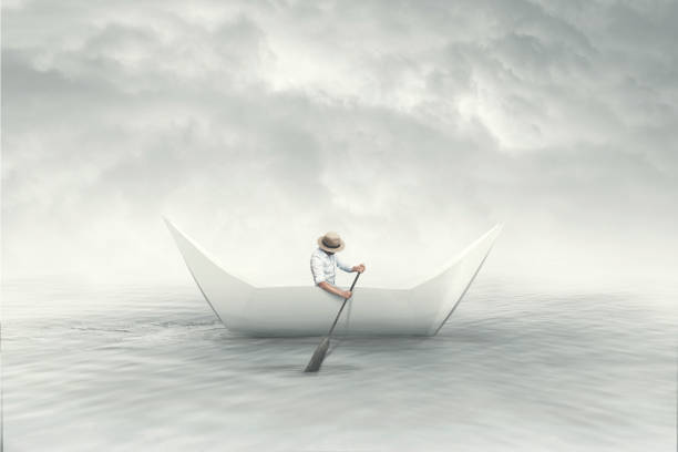 man with hat on a paper origami boat
