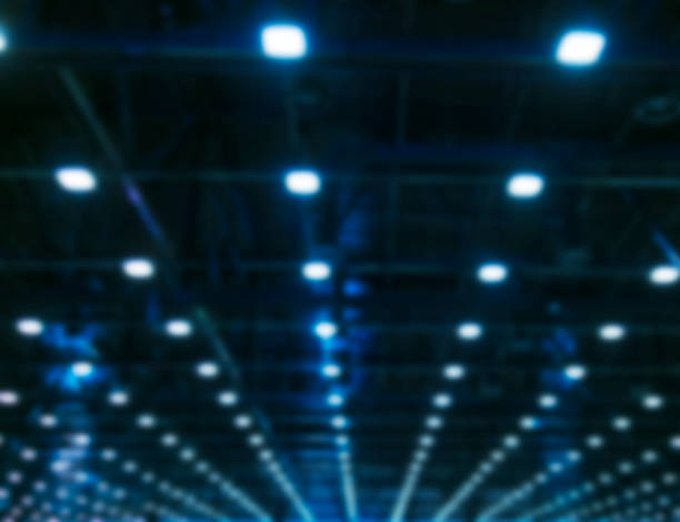istock Blurred background Lights and ventilation system in long line on ceiling of the dark office industrial building, Blur exhibition Hall Ceiling construction 867294374