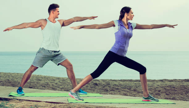 istock Couple do exercises on beach by ocean at daytime 867303756