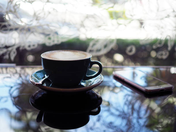 A beautiful cup of hot coffee with Latte Art and plant pot on wooden table background.