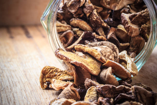 Dry mushrooms in jar on wooden table.