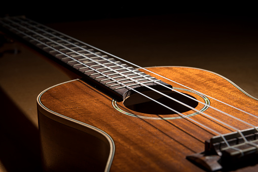 Ukulele sheet music with the strings, neck of the instrument. Music tablature sheet music underneath the strings of an Ukulele.