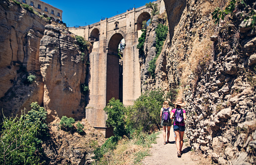 Mother and daughter tourists sightseeing Ronda in Andalusia, Spain. They are walking towards the famous Puente Nuevo bridge.\n\n