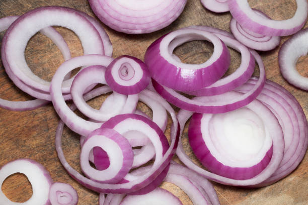 istock Red onions on very old oak wood board 867342300