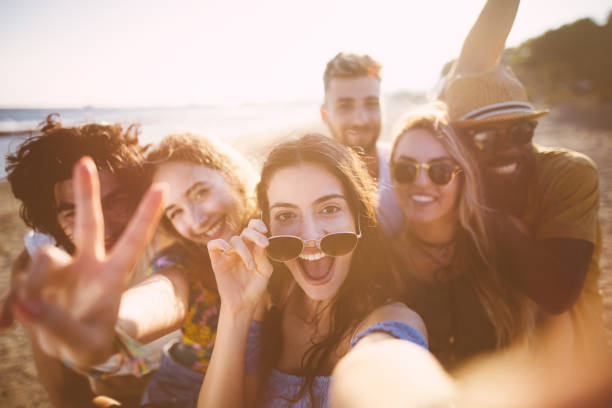 Multi-ethnic friends taking selfies at the beach on summer holidays Young multi-ethnic hipster friends taking selfies at the sea shore on summer island vacations selfie photos stock pictures, royalty-free photos & images